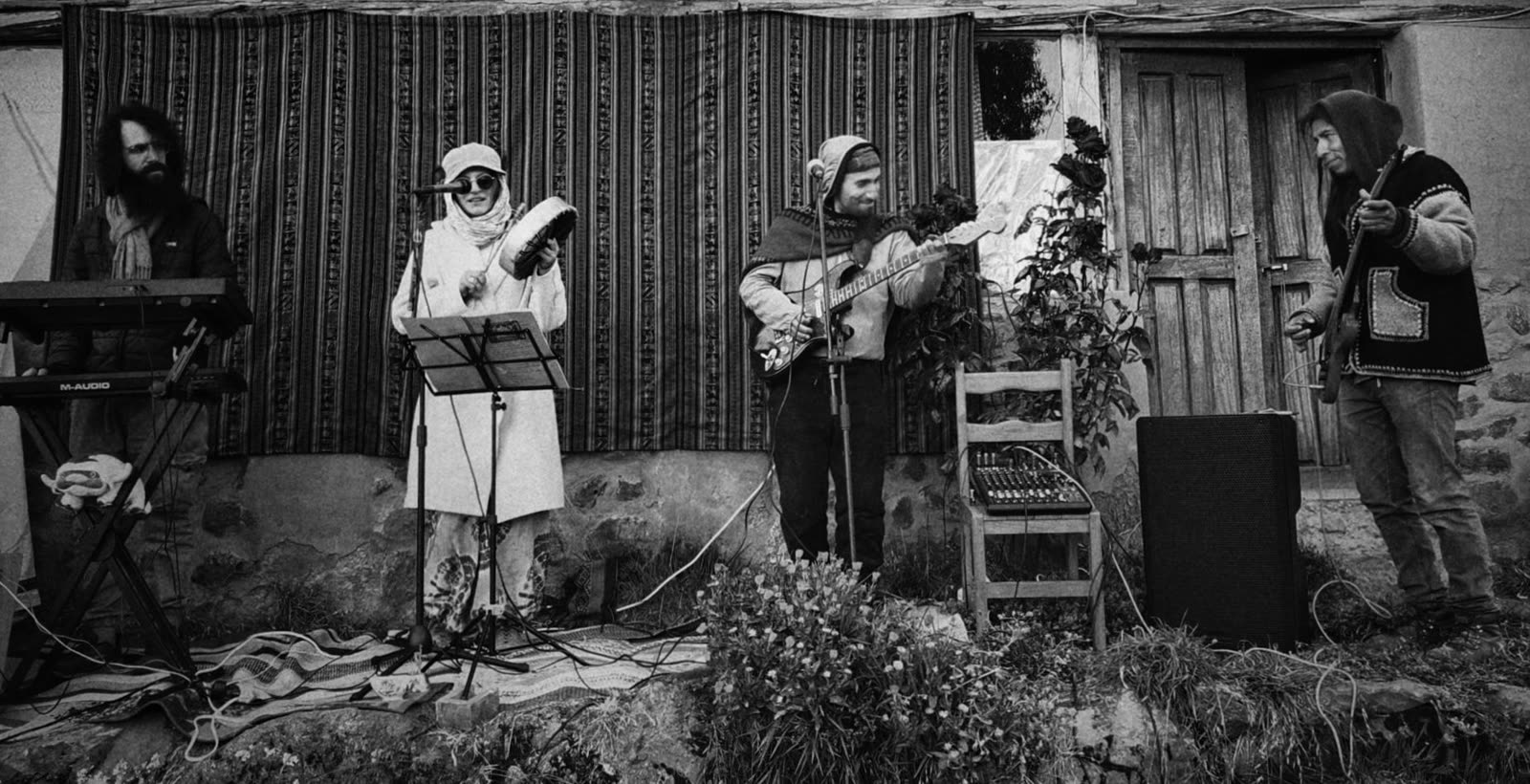 foto en blanco y negro: cinco personas tocan en un patio junto a un muro de adobe — sintet